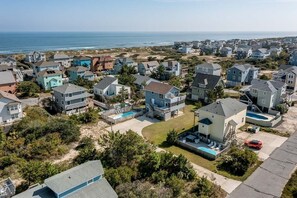 Un barrio residencial con casas, una piscina y vista al océano.