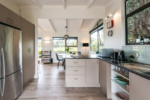 A modern kitchen with a central island, stainless steel appliances, and a view of the outdoors. - Sol Spa Oasis - Surfdale Holiday Home (Surfdale)
