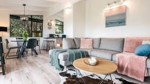 Ein modernes Wohnzimmer mit grauem Sofa, einem Couchtisch und einem Essbereich mit Tisch und Stühlen.