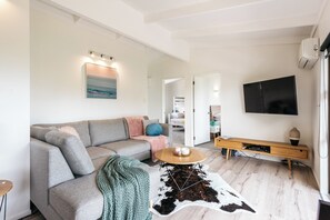 En moderne stue med en grå sofa, et træbord og et ophængt fjernsyn.