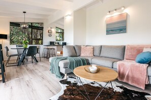 A modern living room with a grey sofa, a coffee table, and a dining area with a table and chairs. - Sol Spa Oasis - Surfdale Holiday Home (Surfdale)