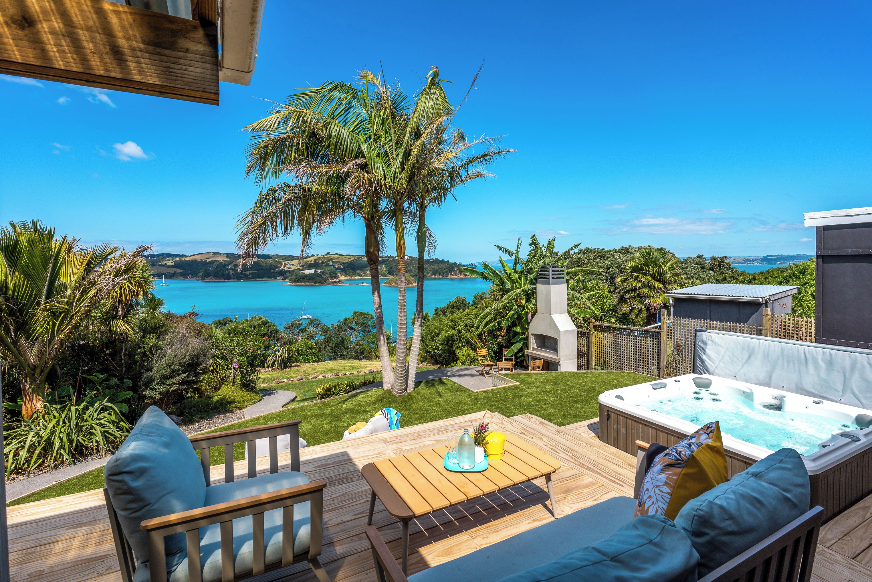 A deck with a hot tub, outdoor furniture, and a view of a lake.
