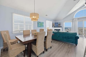 A dining area with wicker chairs, a wooden table, and a hanging light fixture.