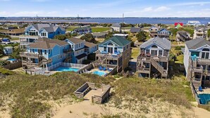 A coastal residential area with houses featuring balconies, a swimming pool, and a beach in the foreground. - Sweet Isabel | Oceanfront | Private Pool, Hot Tub | Nags Head (Nags Head)