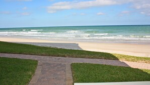 Un camino pavimentado que lleva a una playa con olas rompiendo en la orilla.