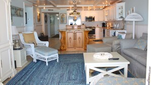A spacious living area with a large island, white furniture, and a kitchen in the background. - Beautifully decorated and completely remodeled with custom woodwork throughout... close proximity to geo thermal pools. NO PETS (New Smyrna Beach)