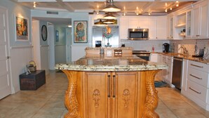 A spacious kitchen with a large island, white cabinetry, stainless steel appliances, and a tiled floor. - Beautifully decorated and completely remodeled with custom woodwork throughout... close proximity to geo thermal pools. NO PETS (New Smyrna Beach)