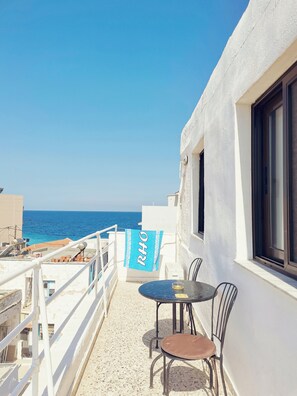 Un balcone con tavolo e sedie, affacciato su un mare cristallino.