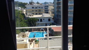 Une vue d’une piscine entourée de personnes et bordée de bâtiments.