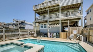 A pool area with a hot tub, wooden deck, and outdoor seating. - Fair Winds | 376 ft from the beach | Private Pool, Hot Tub | Nags Head (Nags Head)