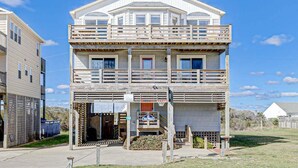 A two-story building with a balcony on the upper floor, a front entrance, and a sign indicating a beach location. - Fair Winds | 376 ft from the beach | Private Pool, Hot Tub | Nags Head (Nags Head)