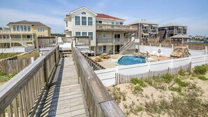 Una propiedad frente a la playa con varias edificaciones, una terraza de madera y una piscina.