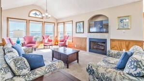 Un salón amplio con chimenea, ventanas grandes y un techo alto.