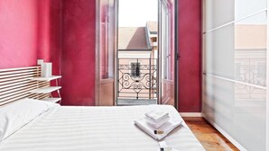 Ein Schlafzimmer mit Bett, Nachttisch, Kleiderschrank und Blick durch eine Tür.