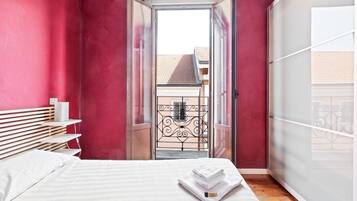 Una camera da letto con un letto, un comodino, un armadio e una vista attraverso una porta.