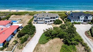 En ejendom ved stranden med et stort hus, en swimmingpool og havudsigt.