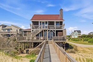 A multi-story house with a balcony, a wooden deck, and a staircase leading to the entrance.