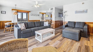 A spacious living area with a grey sofa, a white coffee table, and wicker furniture. - The Porch Life | Oceanfront | Hot Tub | Nags Head (Nags Head)