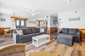 A spacious living area with a grey sofa, a white coffee table, and wicker furniture.