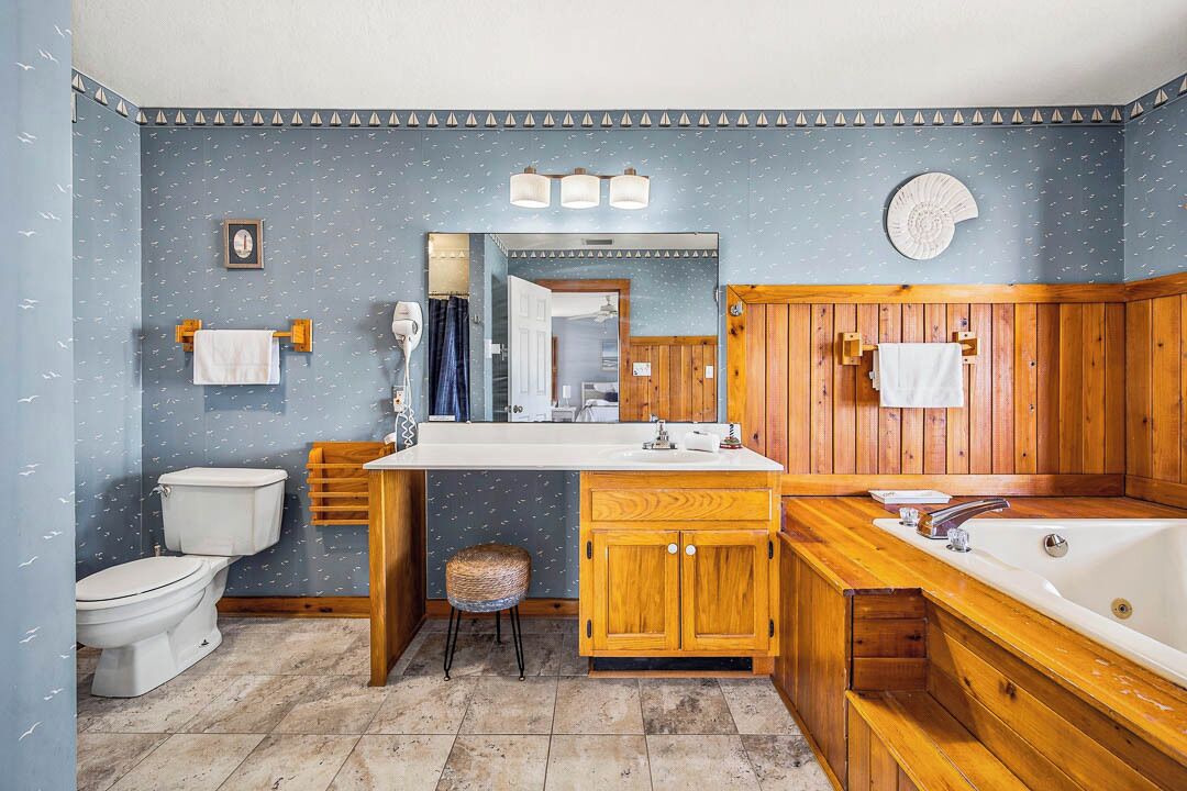 Une salle de bain avec un meuble-lavabo en bois, une baignoire, des toilettes et un miroir.