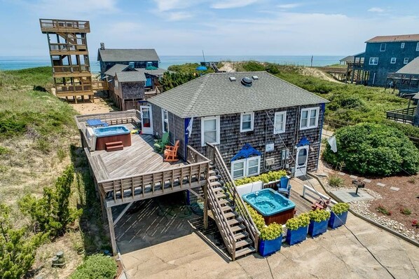 A beachfront property with a large house, multiple decks, and a swimming pool. - The Carriage House I (Upper) | 95 ft from the beach | Dog Friendly, Hot Tub | Nags Head (Nags Head)