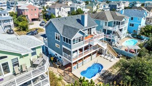 Uma casa de vários andares com uma varanda grande, piscina e vista para o oceano.