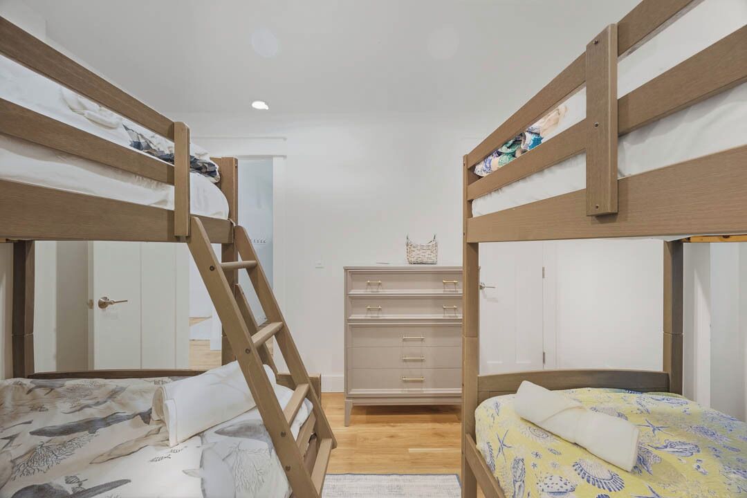 A bunk bed room with a wooden ladder, a dresser, and a door in the background.