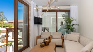 A modern living room with a sofa, chairs, a coffee table, and a TV. - 100m from the beach, kids pool, ping pong, sauna & gym, private sun beds! (Rethymno)