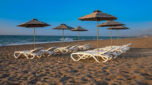 A beach with white lounge chairs and umbrellas aligned in rows. - 100m from the beach, kids pool, ping pong, sauna & gym, private sun beds! (Rethymno)
