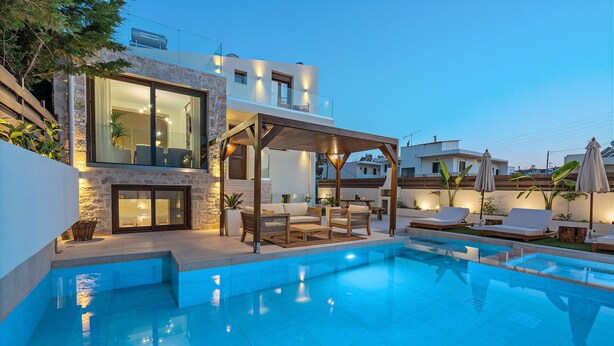 A modern pool area with a covered seating area, stone walls, and a clear blue pool. - 100m from the beach, kids pool, ping pong, sauna & gym, private sun beds! (Rethymno)