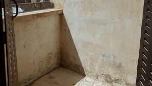A small, enclosed balcony area with a tiled floor and a concrete wall. - Castle House (Al-Karak)