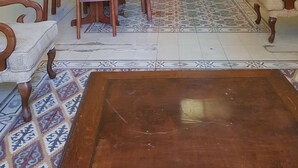 A dining area with a wooden table and chairs, a patterned rug, and a wooden coffee table. - Castle House (Al-Karak)
