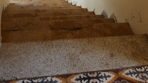 A staircase with a handrail, a wall with peeling paint, and a decorative floral arrangement. - Castle House (Al-Karak)
