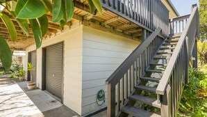A residential building with a wooden staircase leading to a balcony, surrounded by greenery. - Jacaranda Lodge - Whangamata Upstairs Unit (Whangamata)