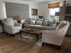 A living room with a sofa, two armchairs, a coffee table, and a patterned rug.