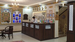 A reception area with a wooden desk, a receptionist, and a reception sign.
