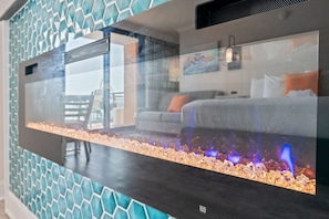 A modern interior with a reflective surface, a patterned wall, and a visible room with a bed and a window.