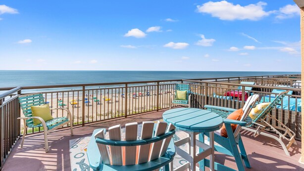 Un balcon avec des chaises et des tables donnant sur une plage.