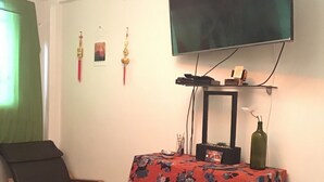 A bedroom with a bed, a chair, a dresser, a TV mounted on the wall, and a small table with a vase. - Depa to share in Mexico City (Only Woman) (Roma Sur)