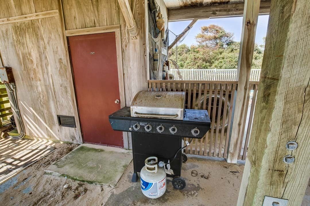 Una estructura de madera con una parrilla para barbacoa y un tanque de propano.
