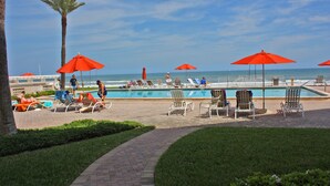 A poolside area with lounge chairs and umbrellas, a pathway, and a view of the ocean. - Steps to south pool deck, pool and ocean from this ground floor, three bedroom, three bath sleeps 8. (New Smyrna Beach)