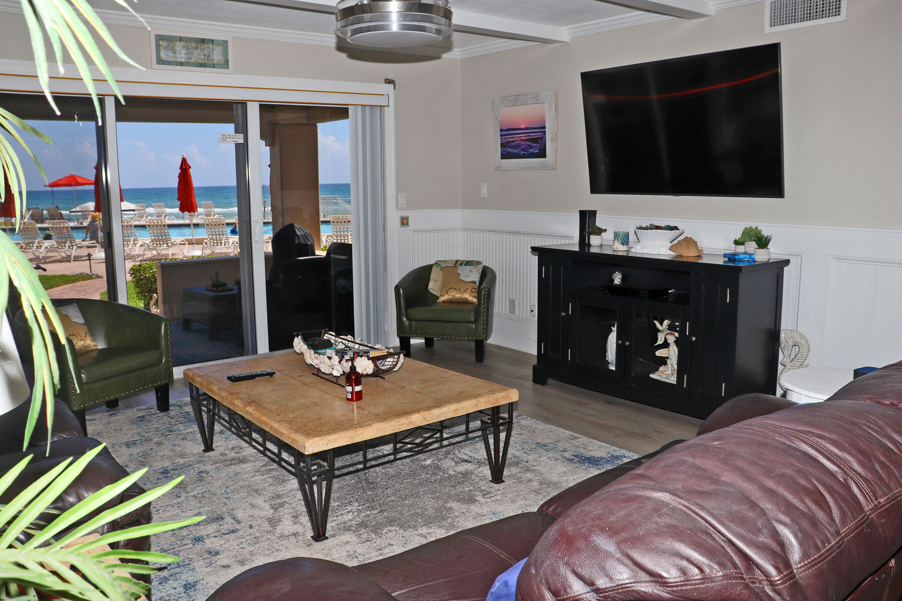 Un salon avec vue sur la plage, une cheminée et un téléviseur à écran plat.