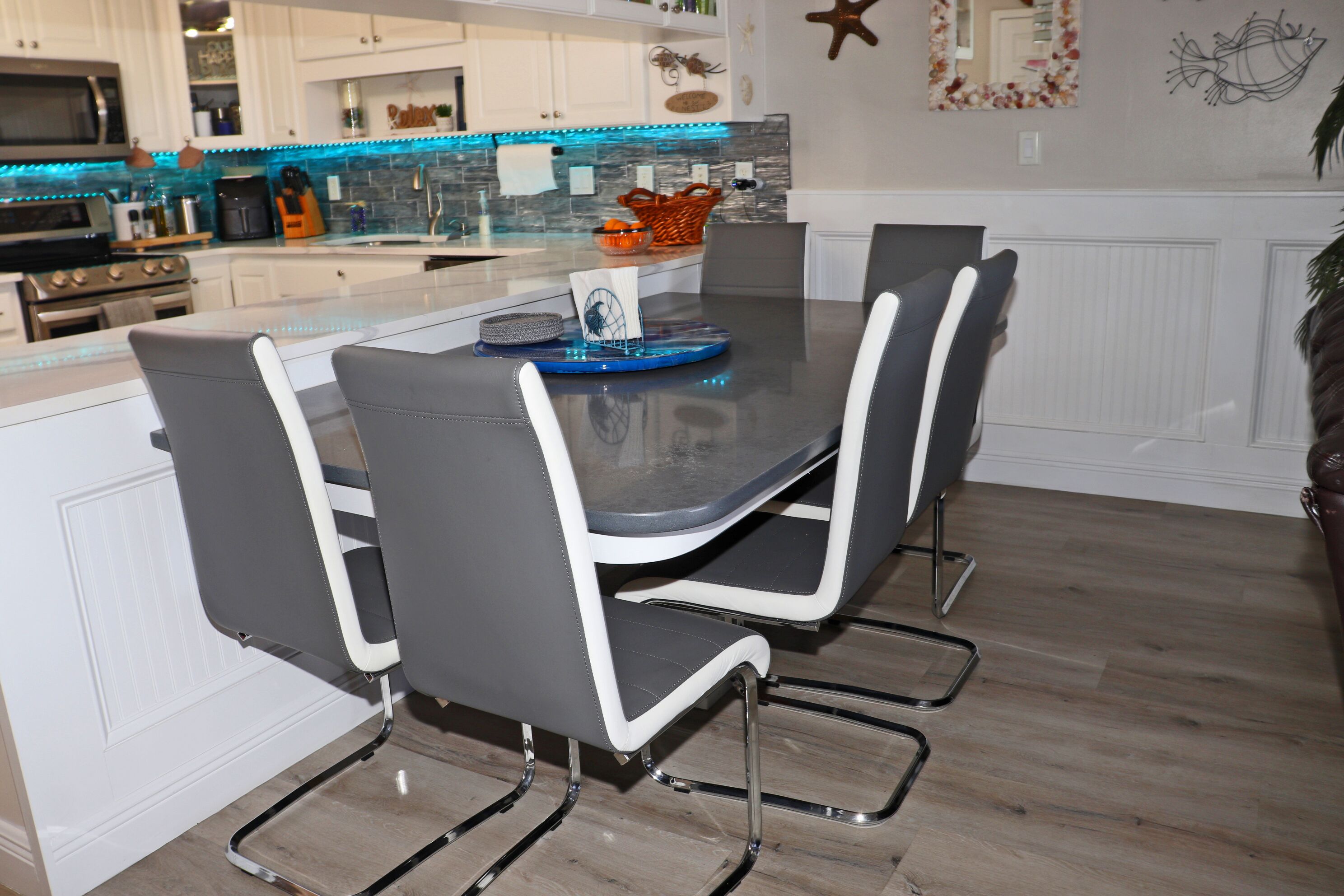 A modern kitchen with a central island, white cabinetry, and a blue countertop.