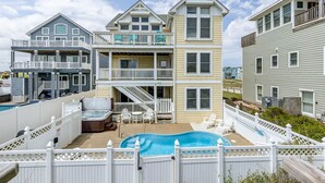 A multi-story residential building with a backyard pool, outdoor seating, and a staircase leading to the upper levels. - Tipsy Mermaid | Oceanfront | Private Pool, Hot Tub | Nags Head (Nags Head)