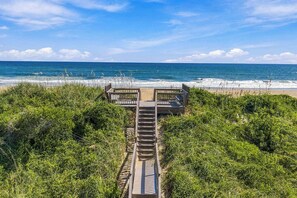 A wooden boardwalk leading to a beach with a clear view of the ocean.