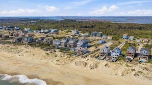 Zona residencial a la costa amb cases, una platja i un bosc de fons.