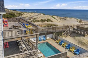 Eine mehrstufige Terrasse mit Pool, Blick auf den Strand und Liegestühlen.