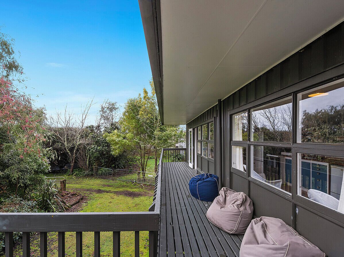 Een balkon met uitzicht op een tuin en bomen.