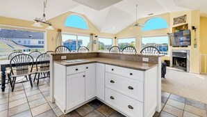 Une cuisine avec des meubles blancs, un plan de travail en granit et un coin repas comprenant des chaises et une table.