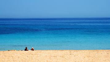 Une plage avec une eau d’un bleu limpide et un rivage sablonneux.